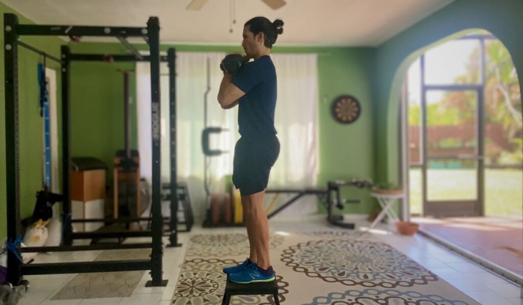 Holding the kettle bells in a front rack position strengthens the core to fight anti-flexion. In this picture a step up exercise now has an added core challenge.